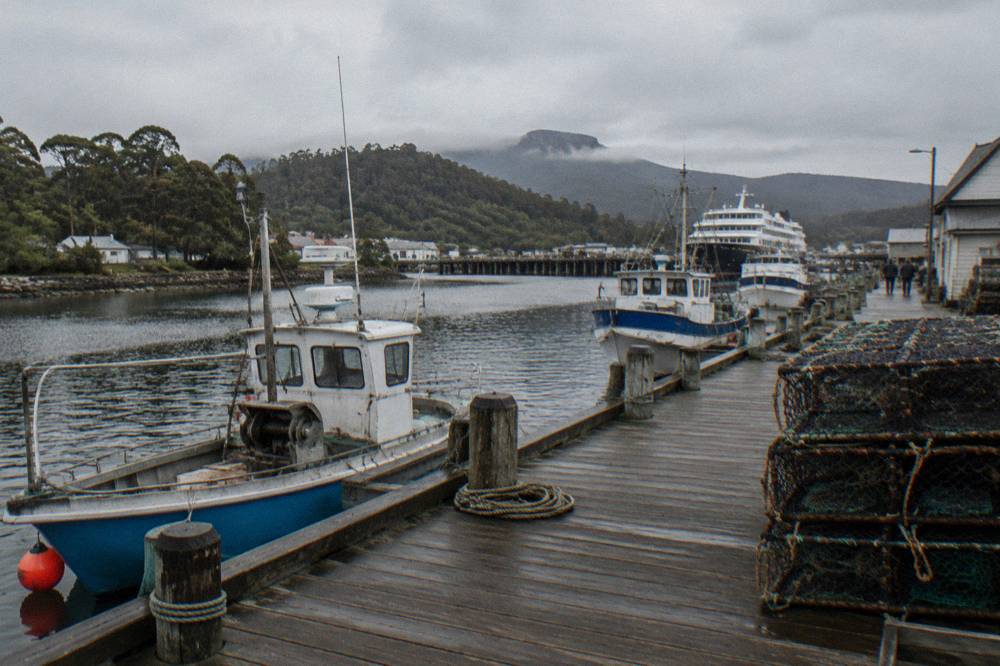 A small timber wharf with boats moored along a waterfront promenade