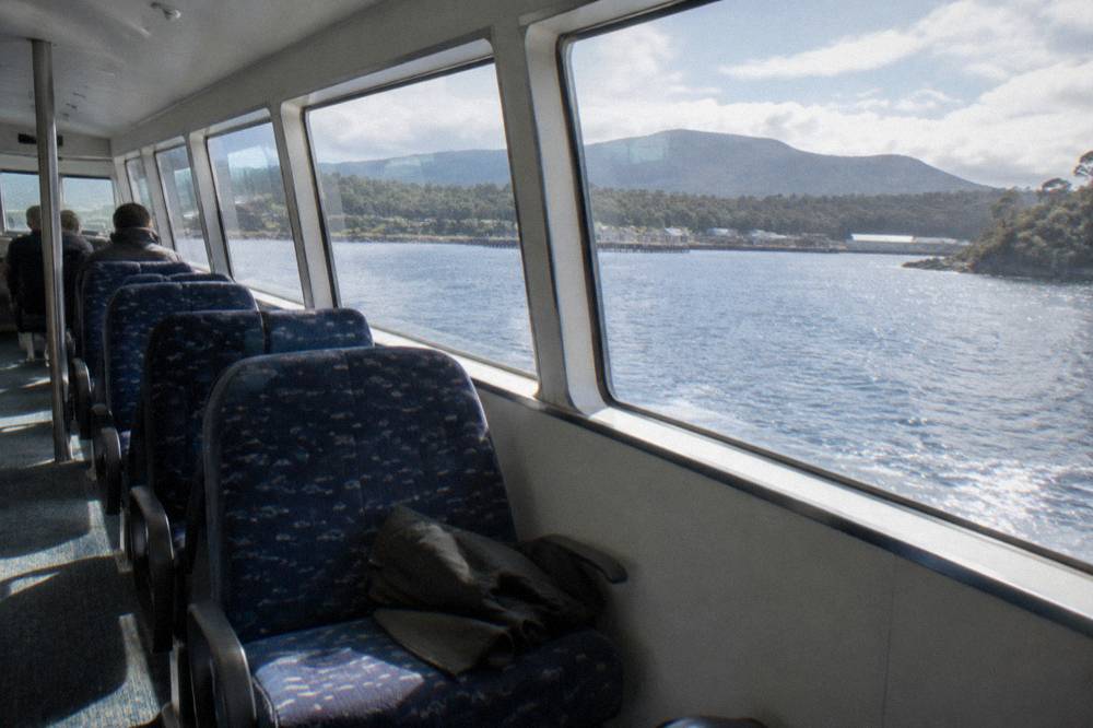 Interior of a cruise catamaran with rows of seats beside wide viewing windows