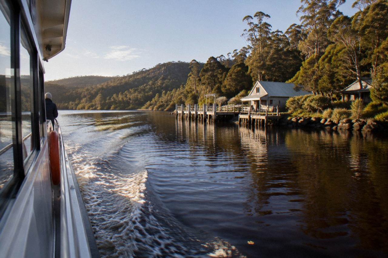 A cruise boat on dark tannin-stained water between forested riverbanks on the Gordon River