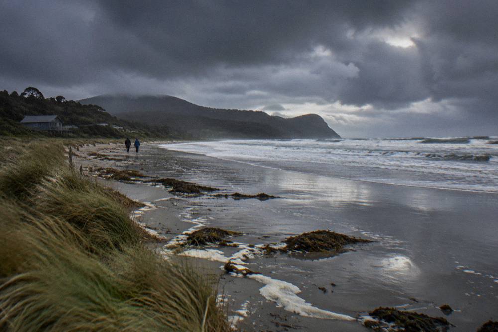 Dark storm clouds passing over a wild ocean beach with wet sand