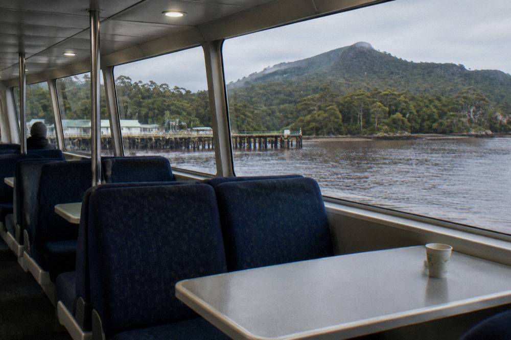 An empty upper deck seating area of a cruise catamaran with views over dark water