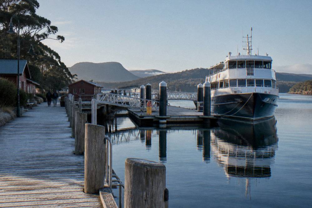 A timber jetty and pontoon beside a moored cruise vessel at a small west coast harbour