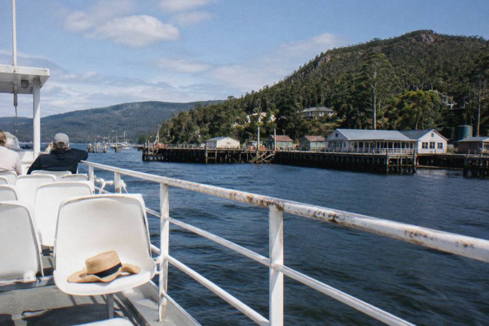 Open upper deck of a cruise catamaran with outdoor seating and wide views across dark harbour water