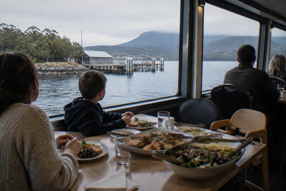 Lunch table set for a family aboard a river cruise with buffet dishes and harbour light through the windows