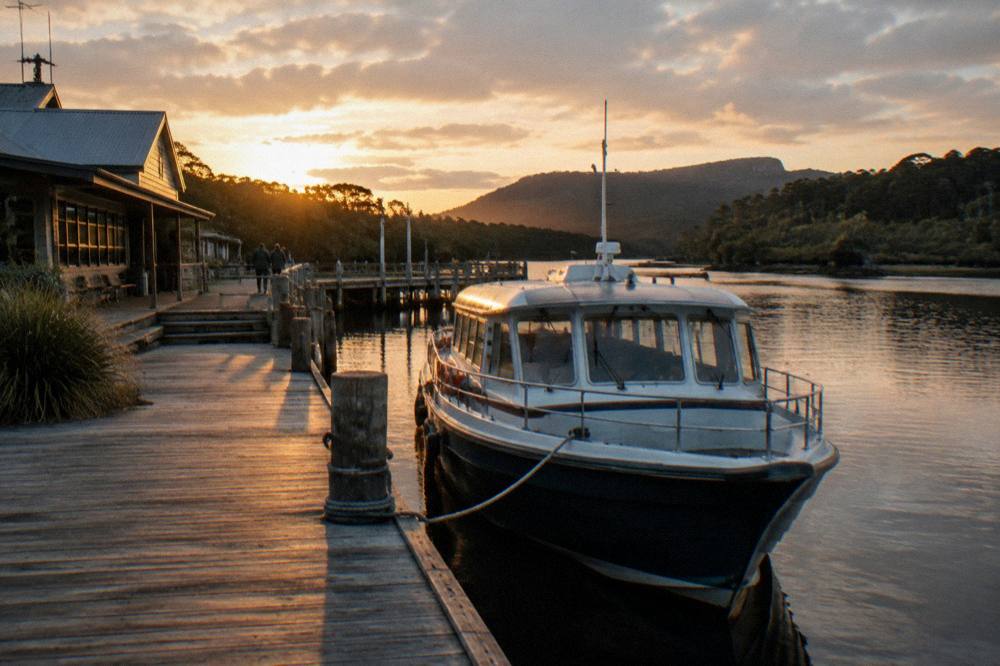 Small cruise boat moored at a timber wharf in golden late afternoon light