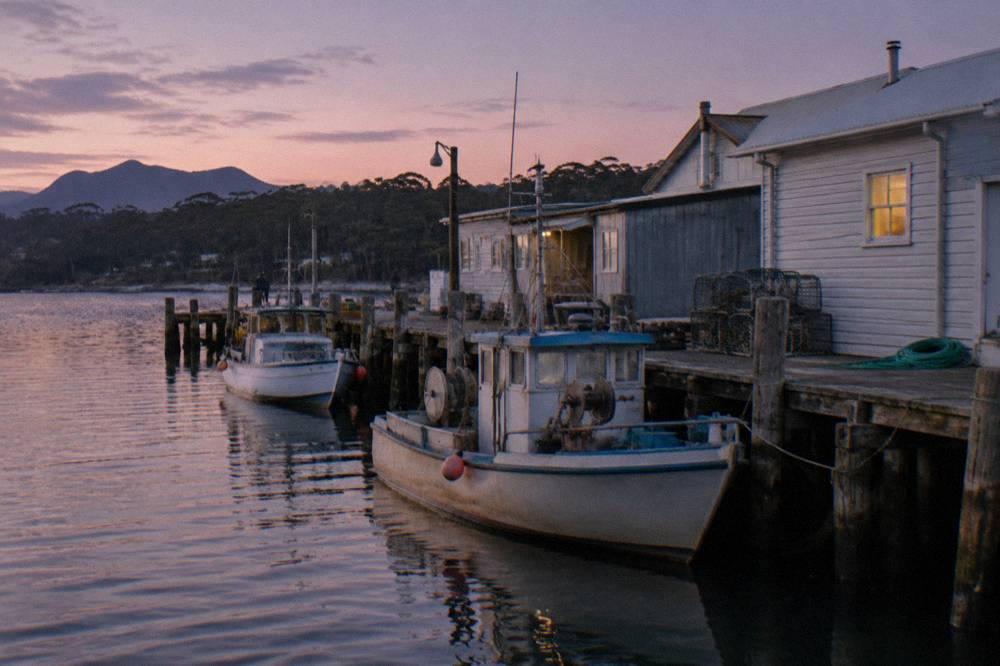 Small west coast town waterfront at dusk with fishing boats moored along a wooden jetty