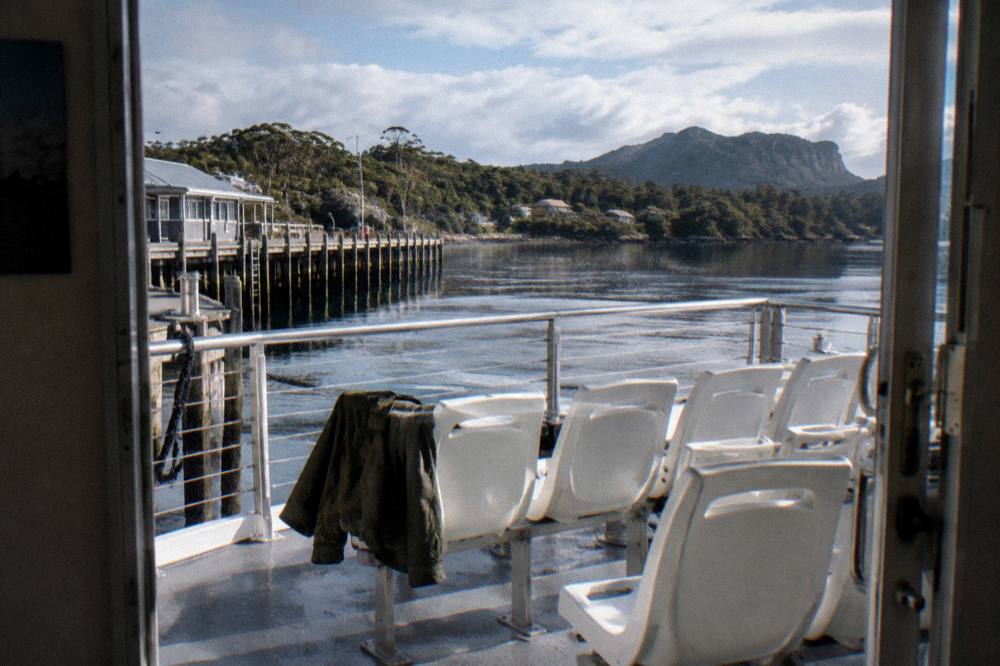Open upper deck of a cruise catamaran with seating and dark harbour water beyond